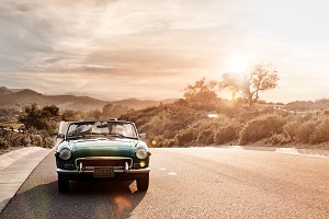 couple driving classic car in sunset