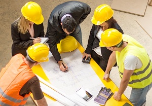 group of contractors sitting around a table looking at blueprints